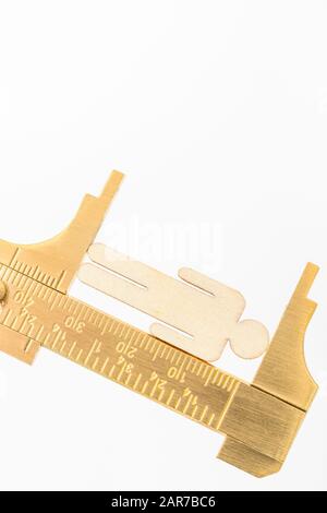 Makro kleine lasergeschnittene Holzfigur und Messing-Zirkel gegen den weißlichen BG. Messung von persönlichen Leistungsindikatoren, demografischen Daten, Produktivität, Stockfoto