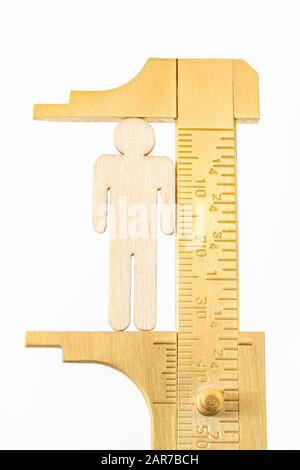 Makro kleine lasergeschnittene Holzfigur und Messing-Zirkel gegen den weißlichen BG. Messung von persönlichen Leistungsindikatoren, demografischen Daten, Produktivität, Stockfoto