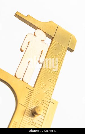 Makro kleine lasergeschnittene Holzfigur und Messing-Zirkel gegen den weißlichen BG. Messung von persönlichen Leistungsindikatoren, demografischen Daten, Produktivität, Stockfoto