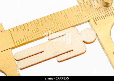 Makro kleine lasergeschnittene Holzfigur und Messing-Zirkel gegen den weißlichen BG. Messung von persönlichen Leistungsindikatoren, demografischen Daten, Produktivität, Stockfoto