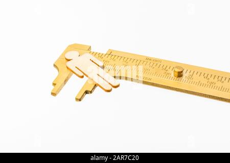 Makro kleine lasergeschnittene Holzfigur und Messing-Zirkel gegen den weißlichen BG. Messung von persönlichen Leistungsindikatoren, demografischen Daten, Produktivität, Stockfoto