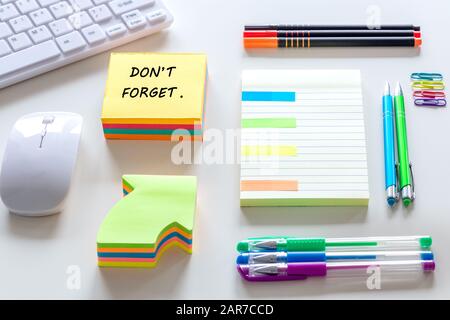 Arbeitsplatz, Büro. Handschriftliche Notiz "nicht Vergessen" Notizbuch mit Platz für Ihre eigene Beschriftung, Tastatur, Stifte, Hefter Stockfoto