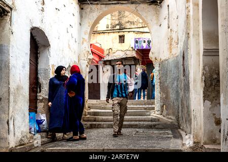 Fes, Marokko - 21.04.2019: Menschen, die in der Straße des Open-Air-Marktbasars in Fez spazieren. Traditionelle nordafrikanische Geschäfte mit handgefertigter Betubung Stockfoto