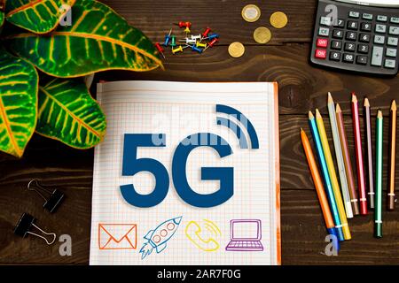 Notizbuch mit Notizen 5G auf dem Bürotisch mit Tools. Konzept mit Elementen der Infografiken. Stockfoto