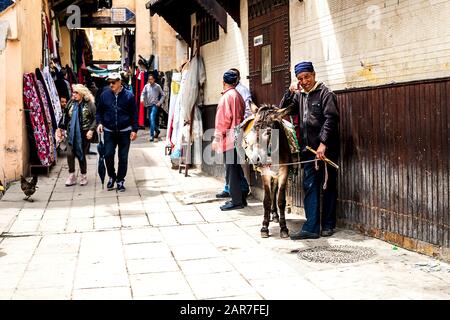 Fes, Marokko - 21.04.2019: Menschen, die in der Straße des Open-Air-Marktbasars in Fez spazieren. Traditionelle nordafrikanische Geschäfte mit handgefertigter Betubung Stockfoto