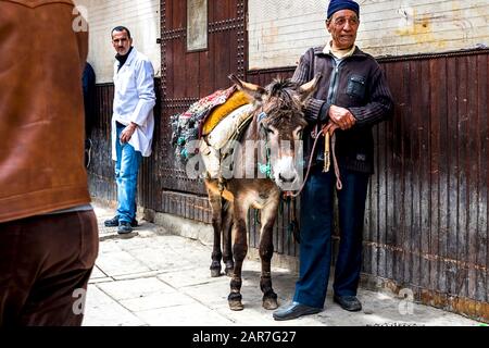 Fes, Marokko - 21.04.2019: Menschen, die in der Straße des Open-Air-Marktbasars in Fez spazieren. Traditionelle nordafrikanische Geschäfte mit handgefertigter Betubung Stockfoto