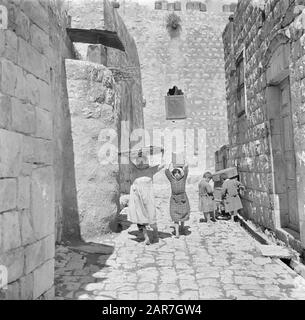 Israel 1948-1949: Peki'in Peki'in Galiläa. Kinder in einer schmalen Straße zwischen Häusern mit massiven Wänden. Zwei junge Mädchen tragen Gegenstände auf dem Kopf Datum: 1948 Ort: Galiläa, Israel, Peki'in Schlüsselwörter: Kinder, Wände, Straßenbilder, Wohnungen Stockfoto