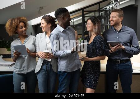 Überfreute multiethnische Mitarbeiter lachen über die Zusammenarbeit im Büro Stockfoto