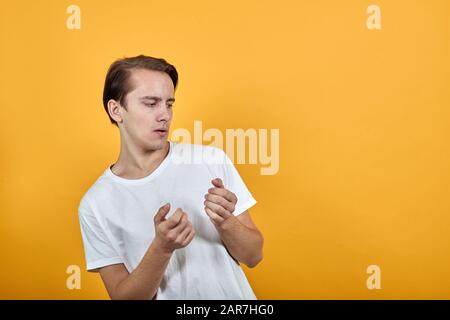 Ein junger Mann in weißem T-Shirt hält seine Hände, in die man etwas einstecken kann. Stockfoto