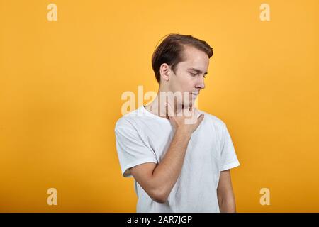 Der Mann im T-Shirt hält sich durch Halsschmerzen an seinem Körper fest. Kalt oder Krankheit im Kerl Stockfoto