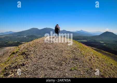 Mann, der auf die Spitze eines Bergrückens eines Vulkankraters in einer bergigen Landschaft, Paricutin, Mexiko, geht Stockfoto