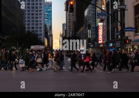 Menschen, die bei Sonnenuntergang auf der 7. av. Und der 34. Kreuzung in Manhattan spazieren gehen Stockfoto