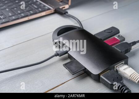 USB Typ-C-Adapter oder Hub in den Laptop mit verschiedenen Accessoires - Pendrives, HDMI, Ethernet, Speicherkarte, Kabel verbunden. Stockfoto