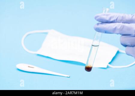 Bluttestkonzept Coronavirus. Reagenzglas mit Patienten Blut, Thermometer und Beatmungsmaske. Chinesischer Ausbruch des Wuhan-Virus. 2019-nKoV biochemisch Stockfoto