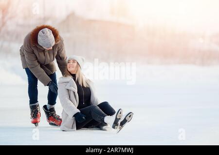 Mädchen zeigt Kerl, bei dem sie nach einer Fallverletzung auf der Eislaufbahn im Winter Schmerzen hat Stockfoto
