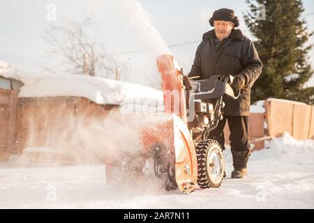 Mann, der Schnee von der Schneefräse des Gebläsemotors entfernt, Eissturm Winter Stockfoto