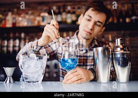 Barman mischt Cocktail-Show mit farbenfrohen alkoholischen Cocktails an der Bar Stockfoto
