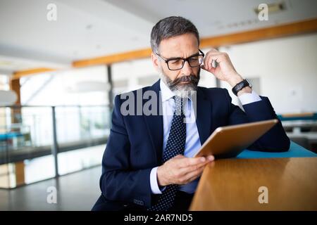Reifen gut aussehender Geschäftsmann mit einem digitalen Tablet im Büro Stockfoto