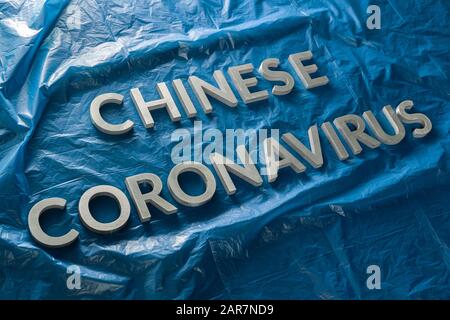 Die Wörter chinesisches Coronavirus wurden mit silbernen Metallbuchstaben auf gelegt Zerknitterte blaue Plastikfolie - diagonale Zusammensetzung Stockfoto