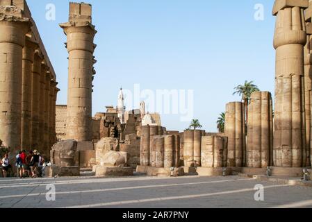 Ägypten, Luxor, Tempel, معبد الاقصر; Theben; Karnak. Ein Seitenhof mit rekonstruierten Säulen und gebrochenen Säulen. Touristen stehen im Schatten. Moschee Stockfoto