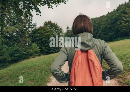 Weibliche Wanderer, die auf dem Fußweg draußen spazieren gehen, Rückansicht der Frau, die morgens wandert Stockfoto