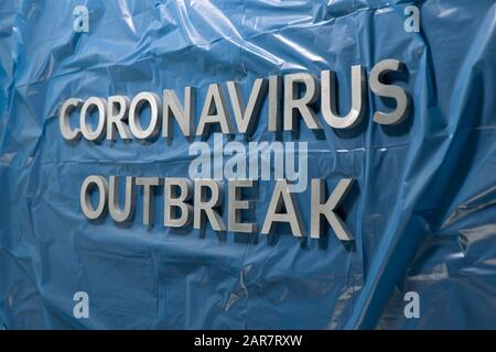 Die Worte Coronavirus Ausbruch gelegt mit silbernen Metallbuchstaben auf Zerknitterte blaue Kunststofffolie Stockfoto