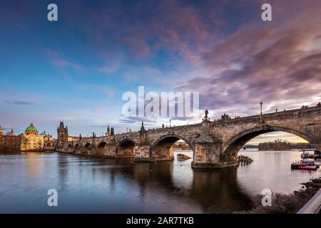 Prag, Tschechische Republik - Schöne lila Sonnenuntergang und Himmel bei der weltberühmten Karlsbrücke (Karluv most) und St. Franz von Assisi Kirche auf einem Winter