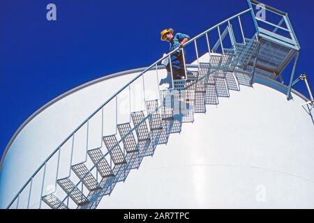 Ein Flüssiggastechniker, der die Treppe eines LNG-Speichertanks hinuntergeht Stockfoto