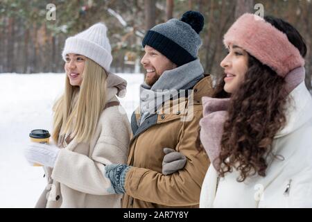 Drei glückliche junge Freunde in legerer Winterkleidung genießen Spaziergänge im Wald Stockfoto