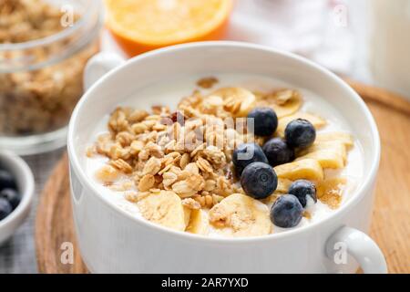 Granola mit Obst und Joghurt in weißer Schüssel mit Nahansicht. Gesundes Frühstück Stockfoto