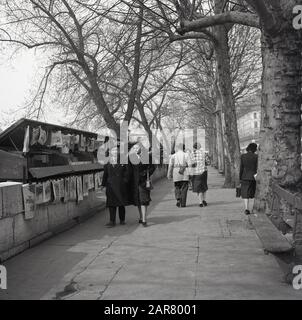 Die 1950er Jahre, historisch, Paare, die entlang des Bürgersteigs am Ufer der seine, Paris, Frankreich, gehen an den Bücherständen vorbei, die als Bouquinistes von Paris bekannt sind und gebrauchte und antiquarische Bücher verkaufen. Stockfoto