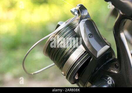 Professionelle Karpfenangeln im Hintergrund. Karpfenangelaufrolle mit Camo-Linie auf dem Schieber. Stockfoto