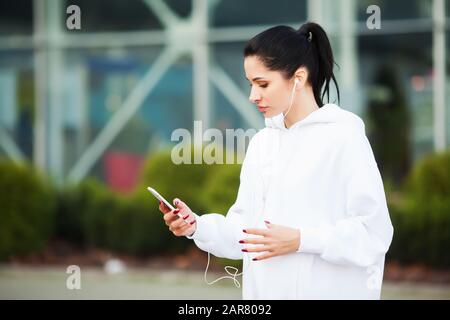 Fitness Mädchen. Hübsche sportliche Mädchen laufen und hören Musik Outdoor. Gesund leben in der großen Stadt Stockfoto