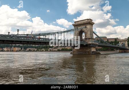 Ein schöner Schuss auf die Kettenbrücke von Secheni in Budapest, über die Donau, mit Blick auf die Skyline der Stadt. Auf der Brücke vorbeifahrende Autos. Tageslicht, Stockfoto