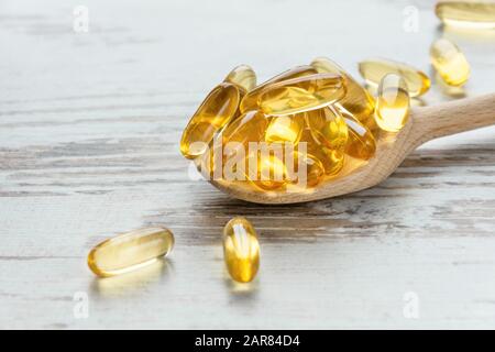 Kabeljau Leberöl Omega 3 Gelkapseln auf einem Löffel auf Holzhintergrund. Fischöl-Vitamine. Stockfoto