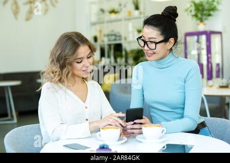 Zwei junge, freundliche Frauen in Casualwear diskutieren über Waren aus dem Online-Shop Stockfoto