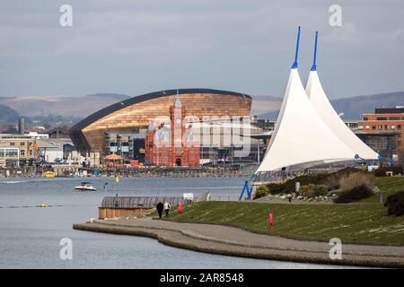 Pavillon mit Menschen, die auf der Barrage mit dem Pierhead Gebäude und dem Millennium Center, Cardiff Bay, Wales, Großbritannien spazieren gehen Stockfoto