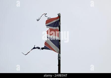 Union Jack, britische Flagge, zerfetzelt, gerissen, fliegen und flattern auf einem grauen Pfosten mit grauem Himmel könnte eine Katastrophe wie Krieg, Sturm oder Brexit illustrieren. Stockfoto