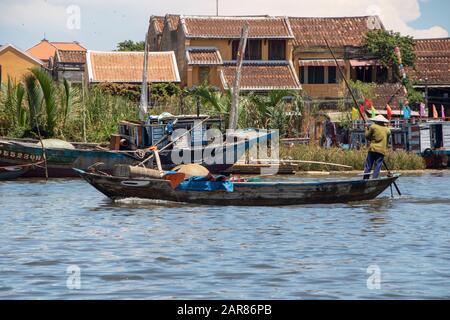 In Hoi An - Vietnam - Am august 2019 - steht ein Fischer auf einem traditionellen Boot, das auf dem Fluss Thu Bon schwimmt Stockfoto