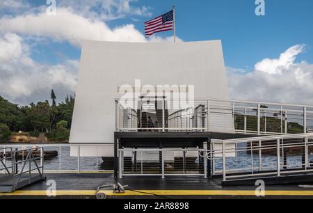 Oahu, Hawaii, USA. - 10. Januar 2020: Pearl Harbor. Dock und Eingang zum White USS Arizona Memorial mit US-Flagge. Blaue Wolkenlandschaft und etwas grünes ol Stockfoto