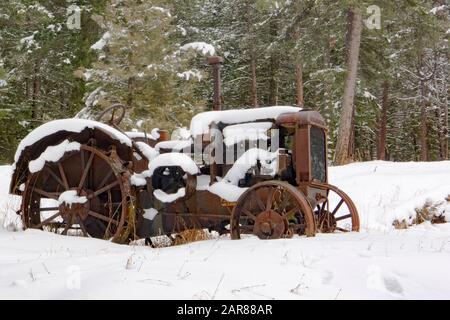 Ein alter Traktor vom Typ Mc Cormick-Deering von 1929 10-20 im Schnee, entlang des Überschwemmungsgebiets Rock Creek südöstlich von Clinton im Missoula County, Montana Stockfoto