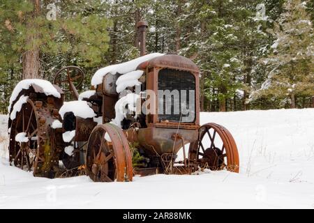 Ein alter Traktor vom Typ Mc Cormick-Deering von 1929 10-20 im Schnee, entlang des Überschwemmungsgebiets Rock Creek südöstlich von Clinton im Missoula County, Montana Stockfoto