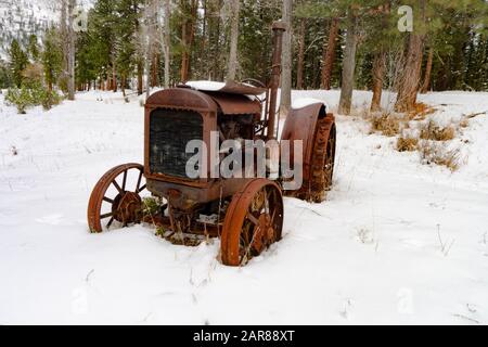 Ein alter Traktor vom Typ Mc Cormick-Deering von 1929 10-20 im Schnee, entlang des Überschwemmungsgebiets Rock Creek südöstlich von Clinton im Missoula County, Montana Stockfoto