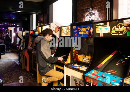 Ein sechzehnjähriger Junge spielt Pac-Man at Versus, eine Arkade und eine Bar in der Province Street in Boston, Massachusetts, USA. Stockfoto