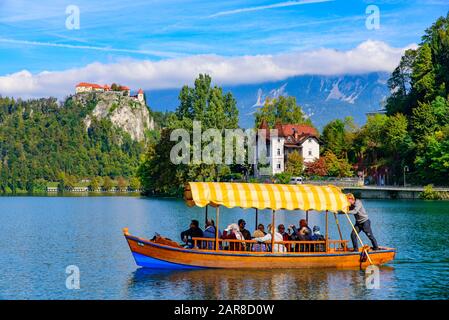 Touristen, die auf dem Bleder See, einem beliebten Touristenziel in Slowenien, ein Boot nehmen Stockfoto