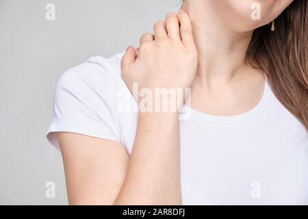 Ein Mädchen in einem weißen T-Shirt berührt wegen starker Schmerzen mit der Hand den Hals. Nahaufnahme. Stockfoto