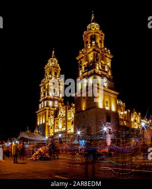 Die Morelia-Kathedrale in der Nacht, mit langer Belichtung, während die Menschen zu Fuß vorbei gehen, im Bundesstaat Michoacan, Mexiko Stockfoto