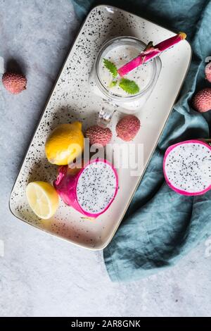 Nahrhafte Drachenfrucht und Lychee Smoothie in einem Glasbecher auf steinernem Grund Stockfoto