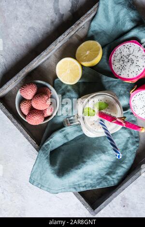 Nahrhafte Drachenfrucht und Lychee Smoothie in einem Glasbecher auf steinernem Grund Stockfoto