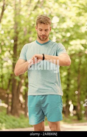 Nützliche Einstellungen. Armband Gadget. Athlet prüfen Fitness tracker Natur Hintergrund. Athleten aus schrittzähler Gadget. Sportler trainieren mit smart Watch. Einrichten fitness Tracker. Fitness Trainer. Stockfoto